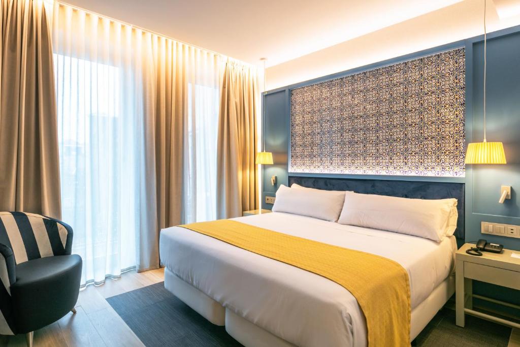 a hotel room with a large bed and a large window at Catalonia Porto in Porto