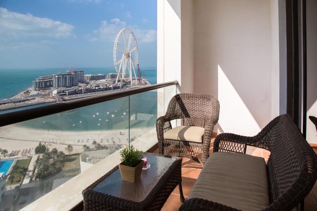 a balcony with a table and chairs and a ferris wheel at HiGuests - Unique Duplex Penthouse in JBR with Sea Views in Dubai