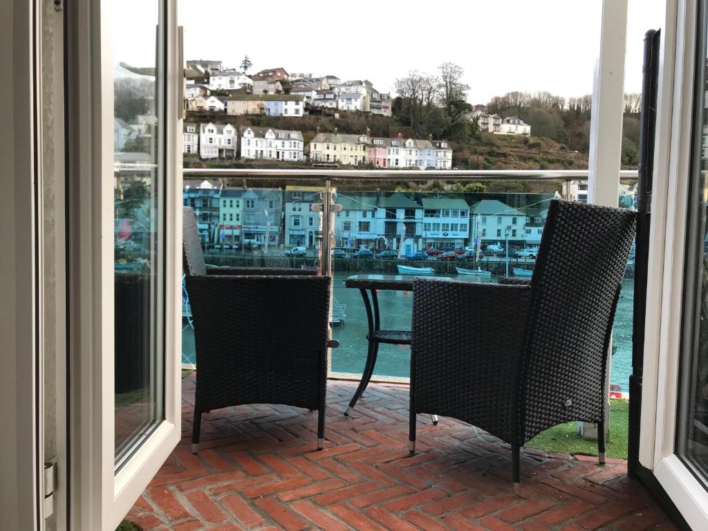 a balcony with a table and chairs looking out at the water at Shellseekers Guest House in Looe
