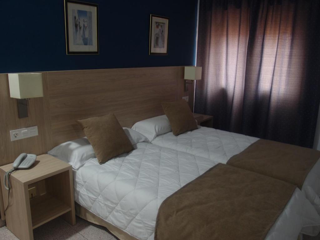 Hotel Catalán Puerto Real في بويرتو ريال: غرفة في الفندق بسرير وهاتف على طاولة