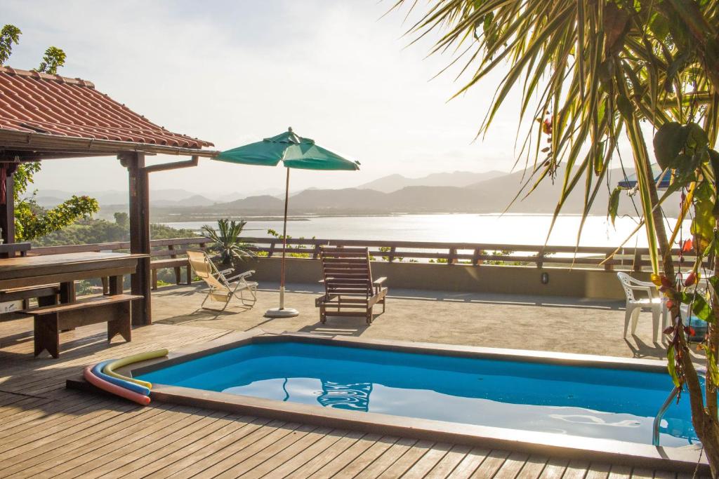 - une piscine sur une terrasse avec une table et un parasol dans l'établissement Casa em CondomÍnio Fechado com Vista para Lagoa, à Garopaba