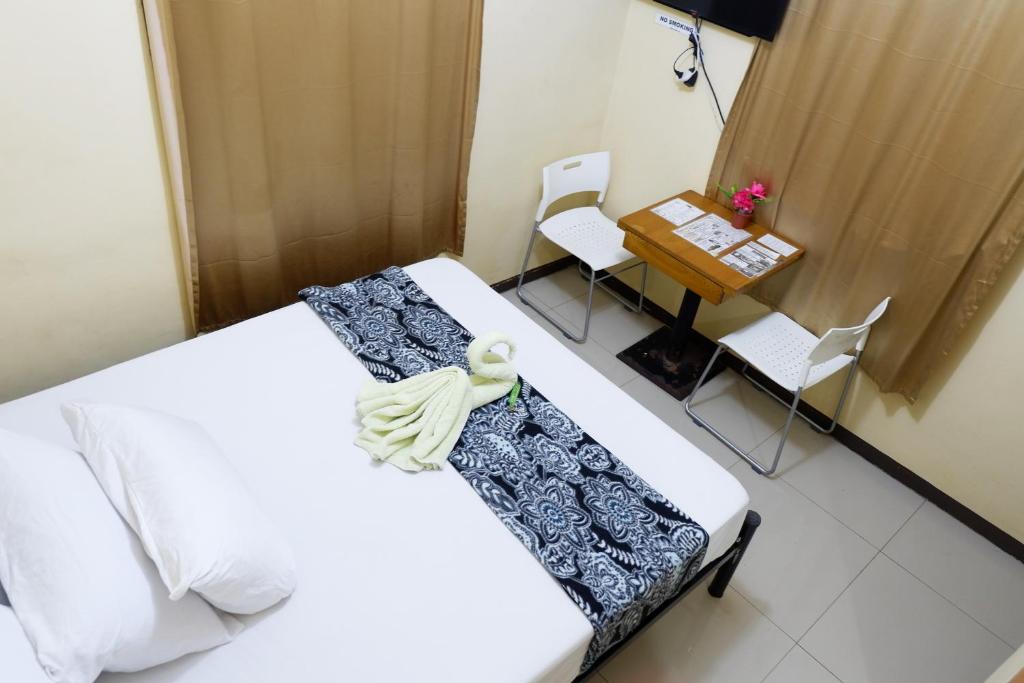Cette chambre comprend un lit, une table et des chaises. dans l'établissement Alpina Monte Carlo Travellers Inn, à Tagaytay