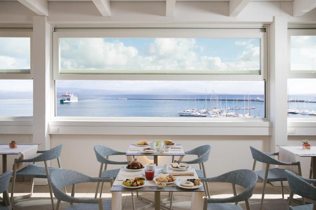 a restaurant with tables and chairs and a large window at Lu' Hotel Riviera in Carloforte