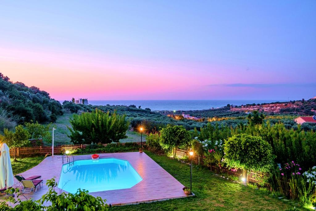 une villa avec une piscine au coucher du soleil dans l'établissement Villa Evelina, à Adelianos Kampos