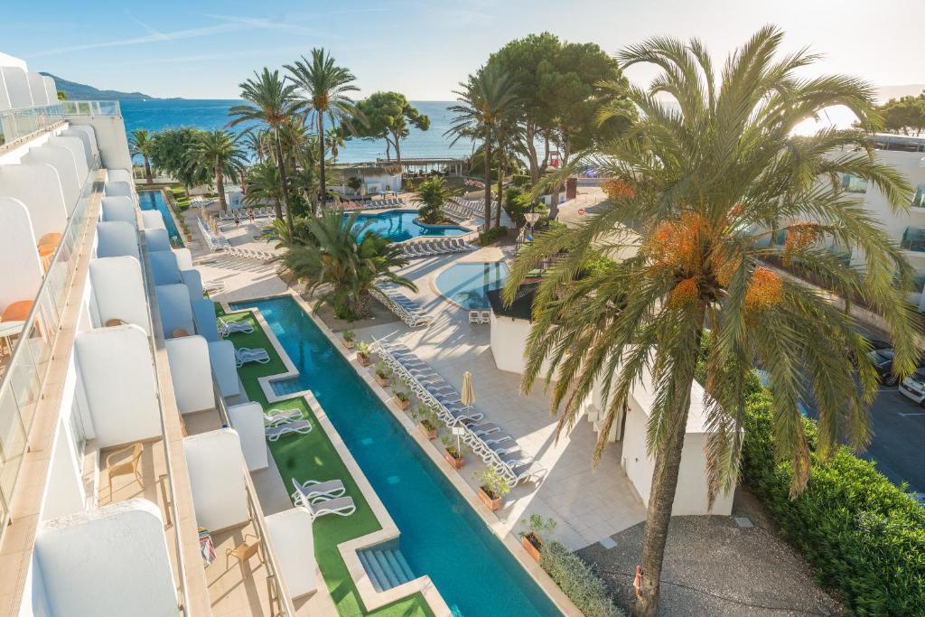 an aerial view of a resort with a pool and palm trees at Aparthotel Ses Fotges in Playa de Muro
