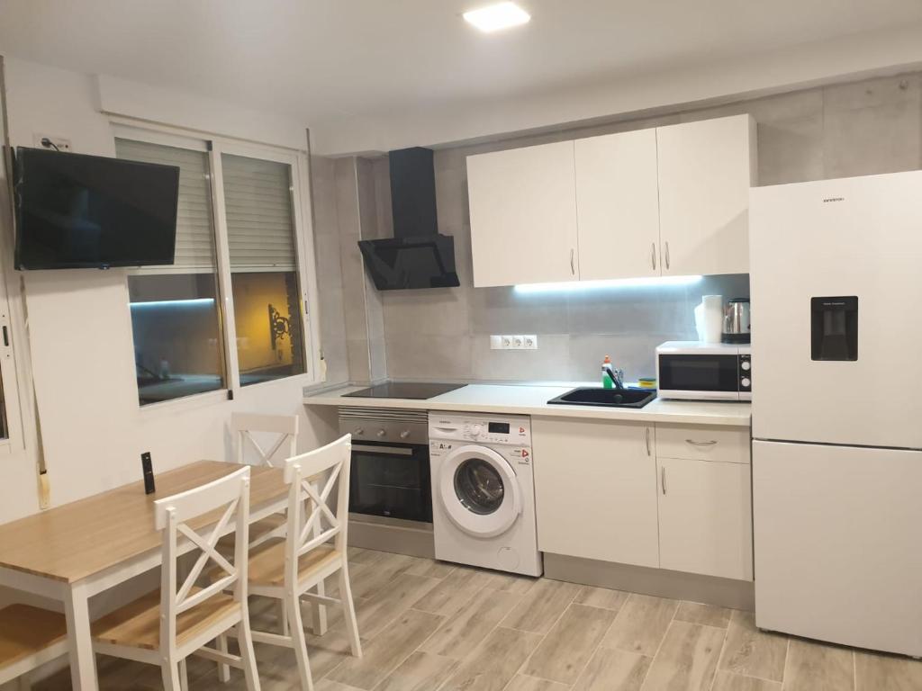 cocina con armarios blancos, mesa y microondas en Style Apartments Cabanyal Marina Beach, en Valencia
