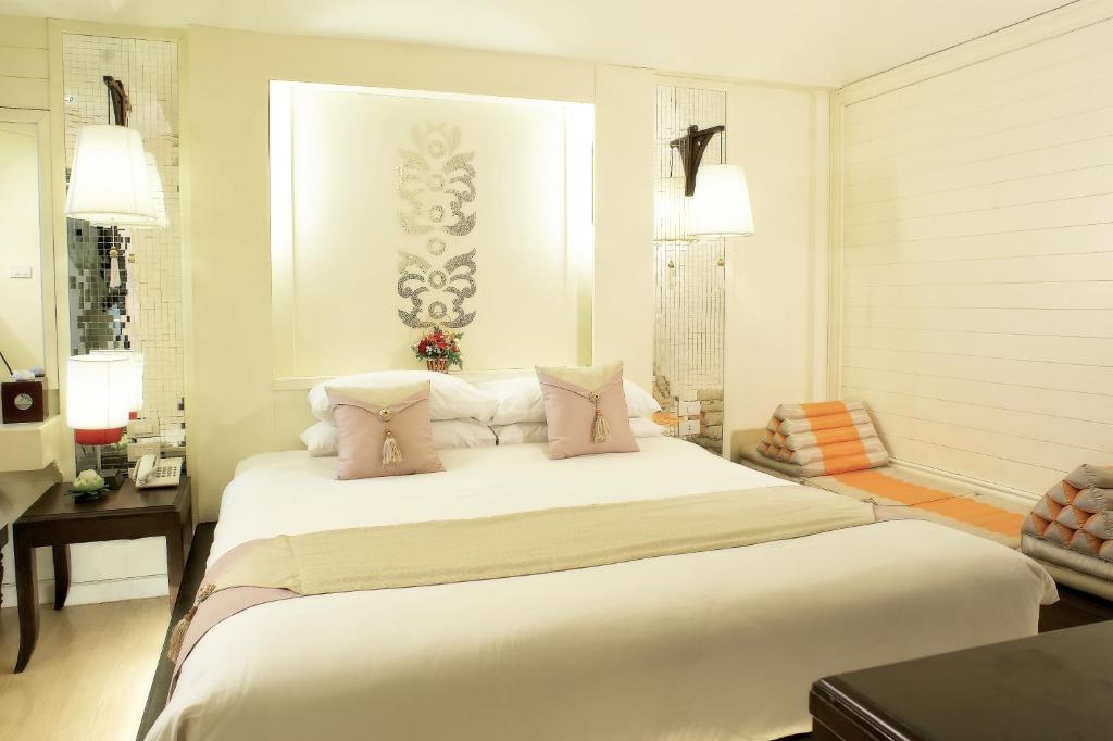 a bedroom with a large white bed with pink pillows at Chiangmai Gate Hotel in Chiang Mai