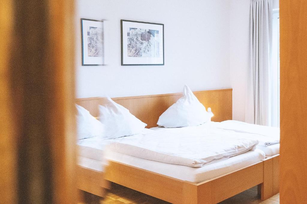 1 dormitorio con 1 cama con sábanas y almohadas blancas en Ludgerusbrunnen Hotel Mertens, en Billerbeck