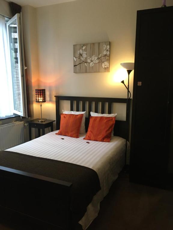 a bedroom with a bed with two orange pillows at Eurotel in Liège