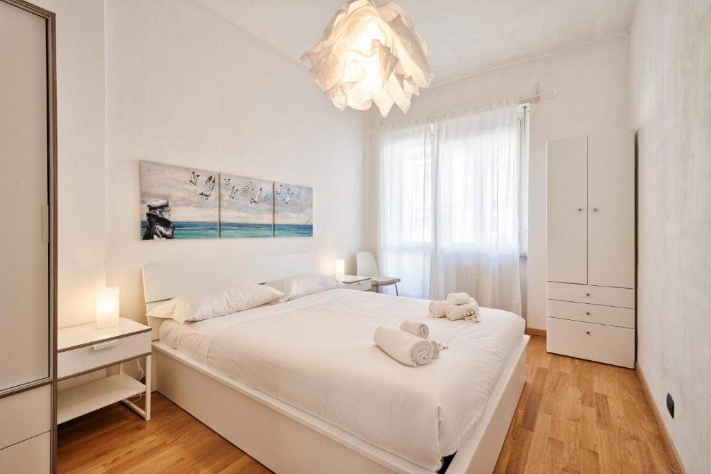 - une chambre blanche avec un grand lit et un lustre dans l'établissement Toc-Toc Apartment a 10 min dall'Ospedale Maria Vittoria, à Turin