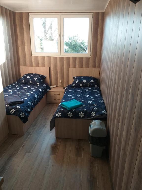 ein kleines Schlafzimmer mit 2 Betten und einem Fenster in der Unterkunft 2 osobowe kawalerki w domkach FreezerHause Kozery- NoclegiGrodziskPL 792-535-535 in Grodzisk Mazowiecki
