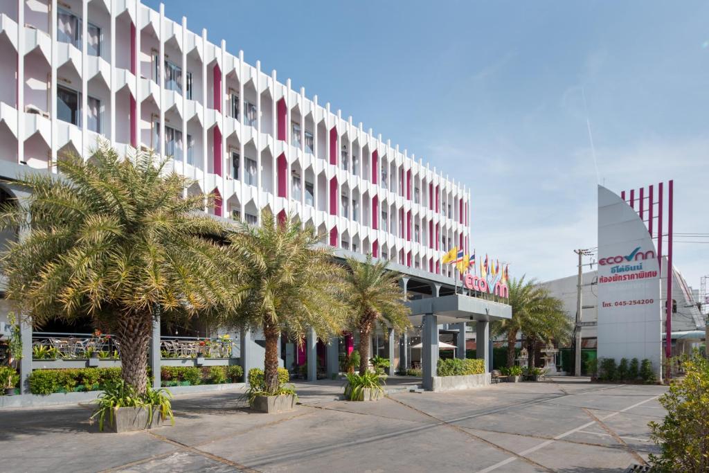 a large building with palm trees in front of it at Eco Inn Lite Ubon Ratchathani in Ubon Ratchathani