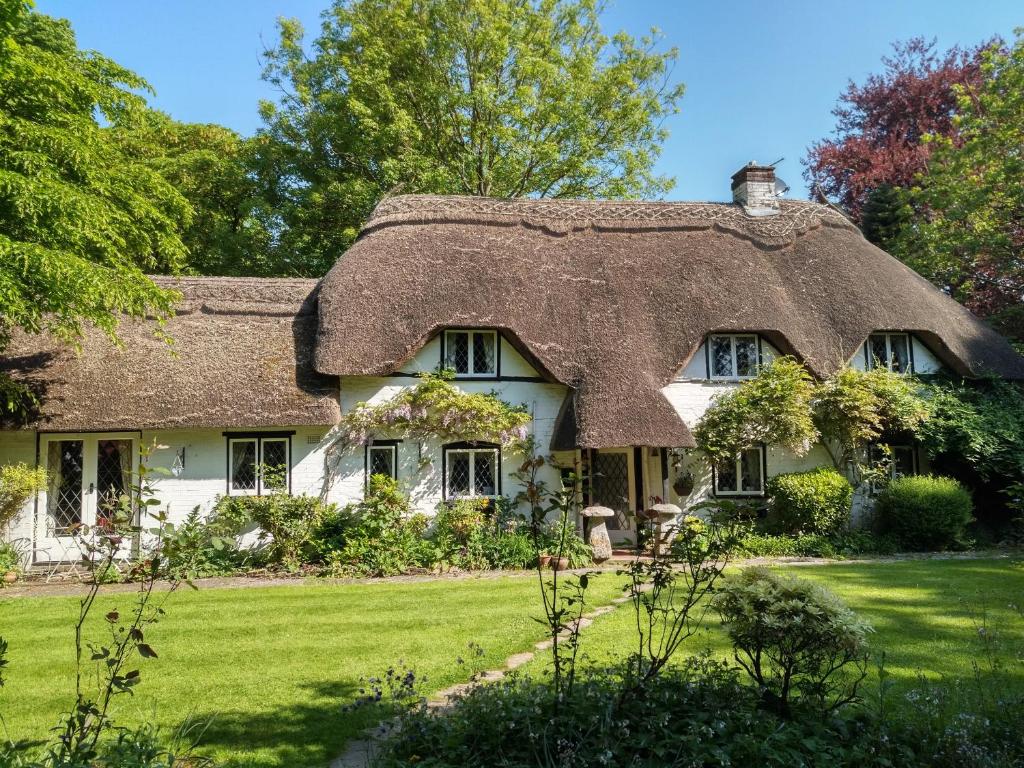 a thatch roofed house with a grass at Thatched Eaves in Ibsley