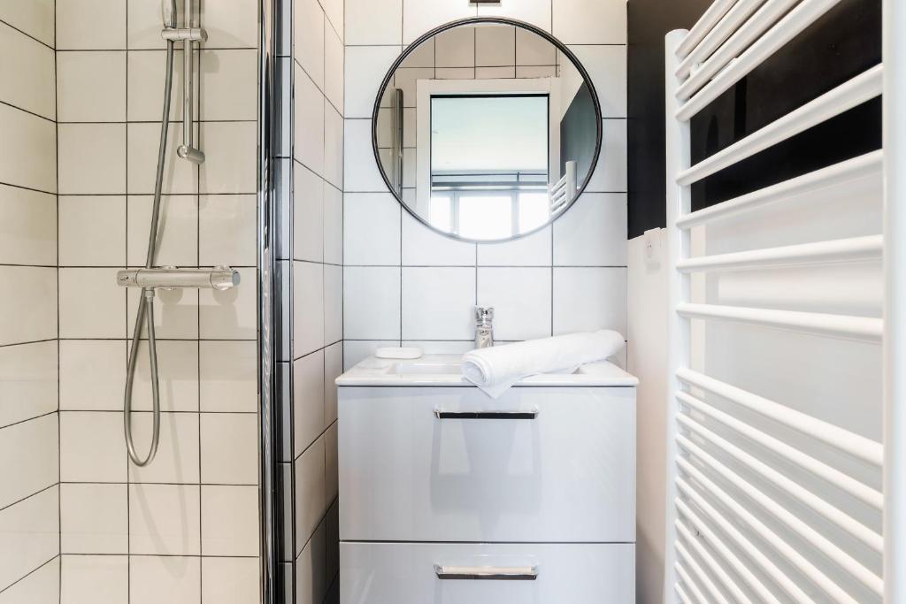 a white bathroom with a sink and a mirror at GuestReady - Charming studio in Issy-les-Moulineaux in Issy-les-Moulineaux