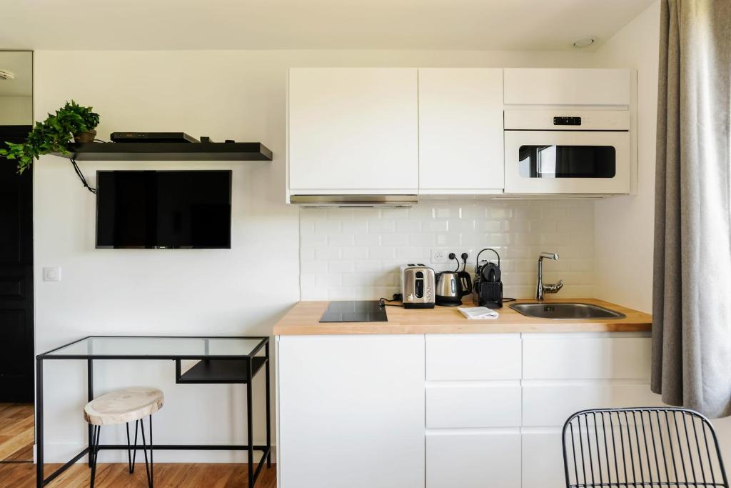 a kitchen with white cabinets and a counter top at GuestReady - Charming studio in Issy-les-Moulineaux in Issy-les-Moulineaux