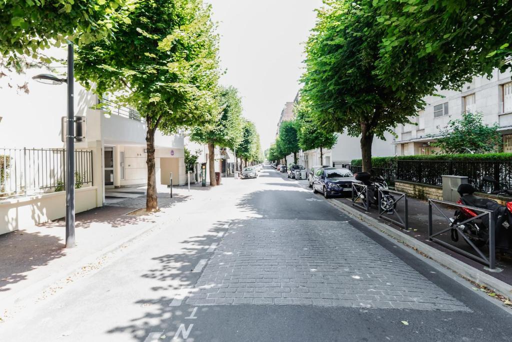 an empty street with trees and parked cars at GuestReady - Charming studio in Issy-les-Moulineaux in Issy-les-Moulineaux