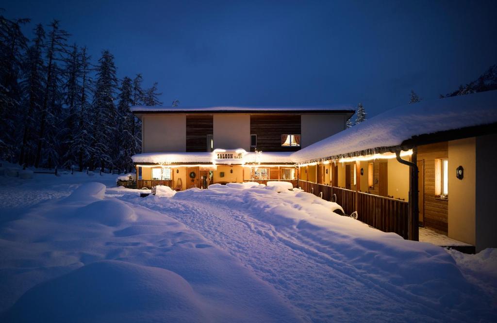 a house is covered in snow at night at Reitstall und Saloon San Jon in Scuol