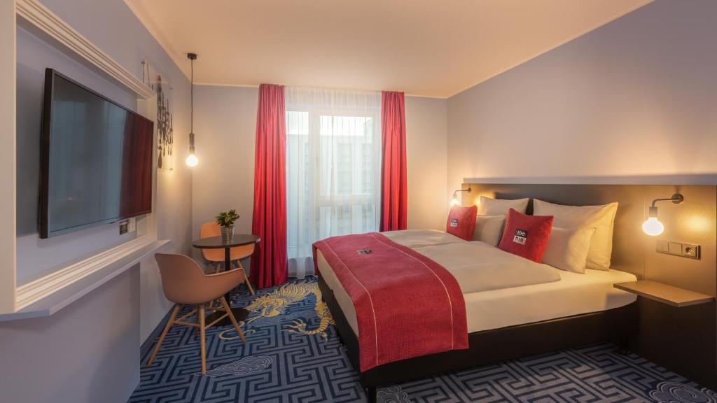 a hotel room with a bed, chair, and nightstand at the niu Mood in Mainz