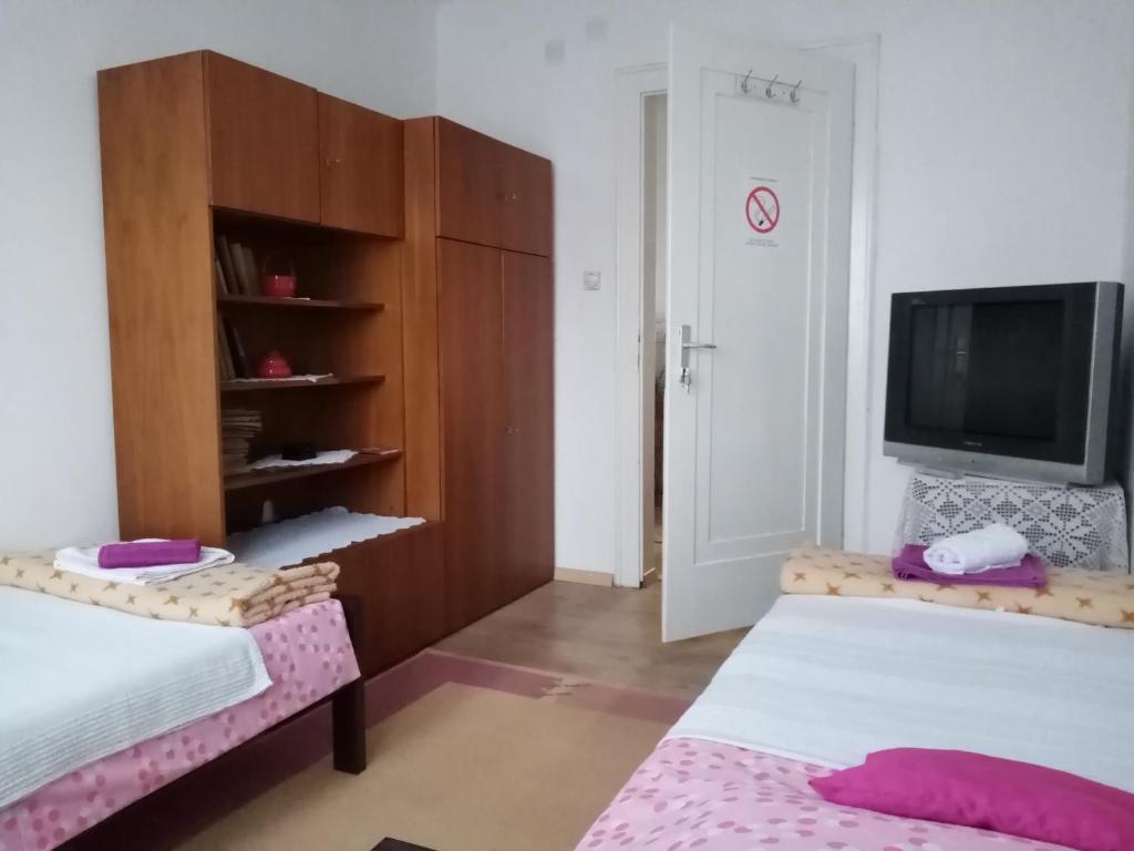 Habitación pequeña con 2 camas y TV. en Vila I, en Niška Banja