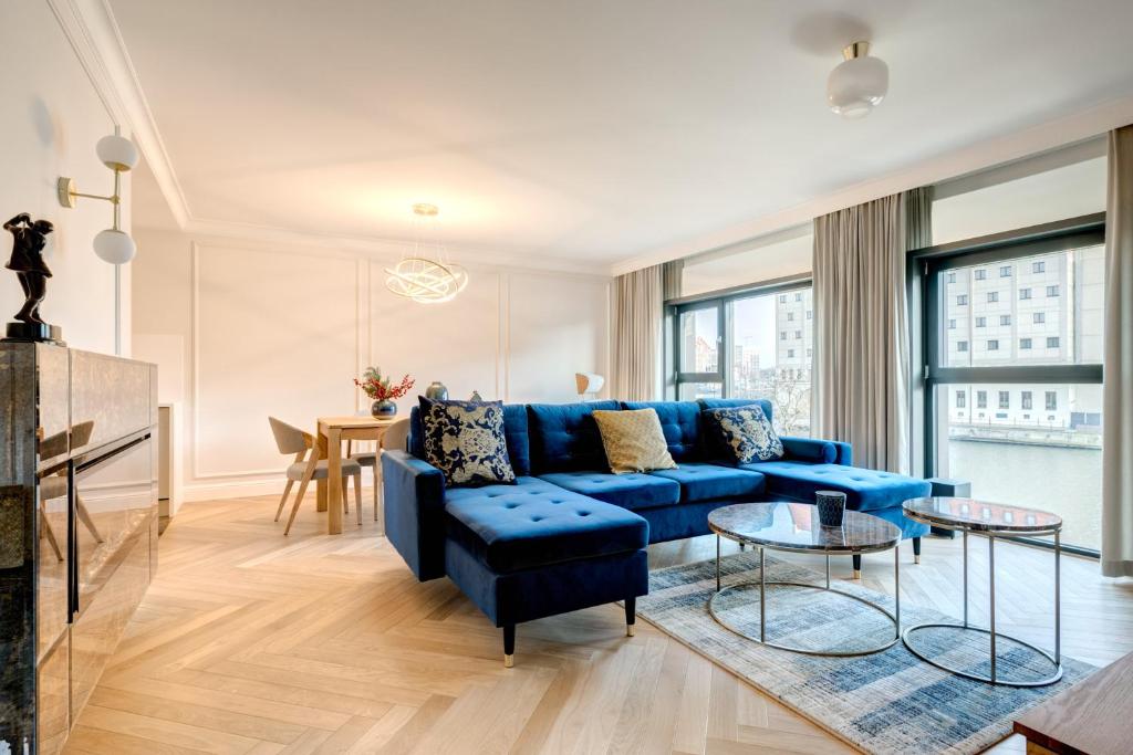 a living room with a blue couch and a table at Dom & House - Apartments Winter Residence in Gdańsk