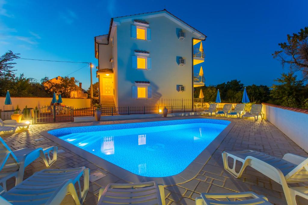 una piscina con sedie e un edificio sullo sfondo di Palmer Residence Krk a Dobrinj