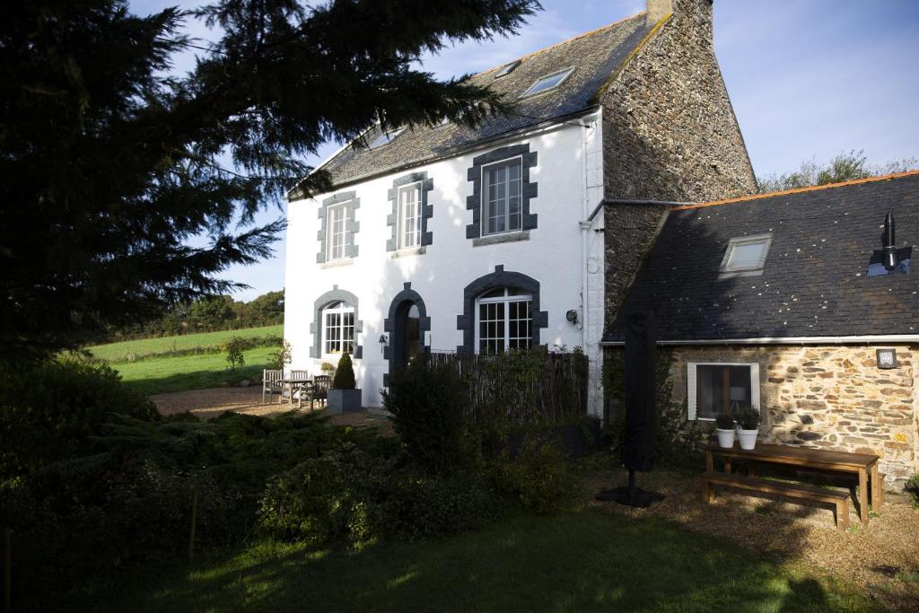 a white house with a stone building at La Colline des Renards Chambres in Locmaria-Berrien