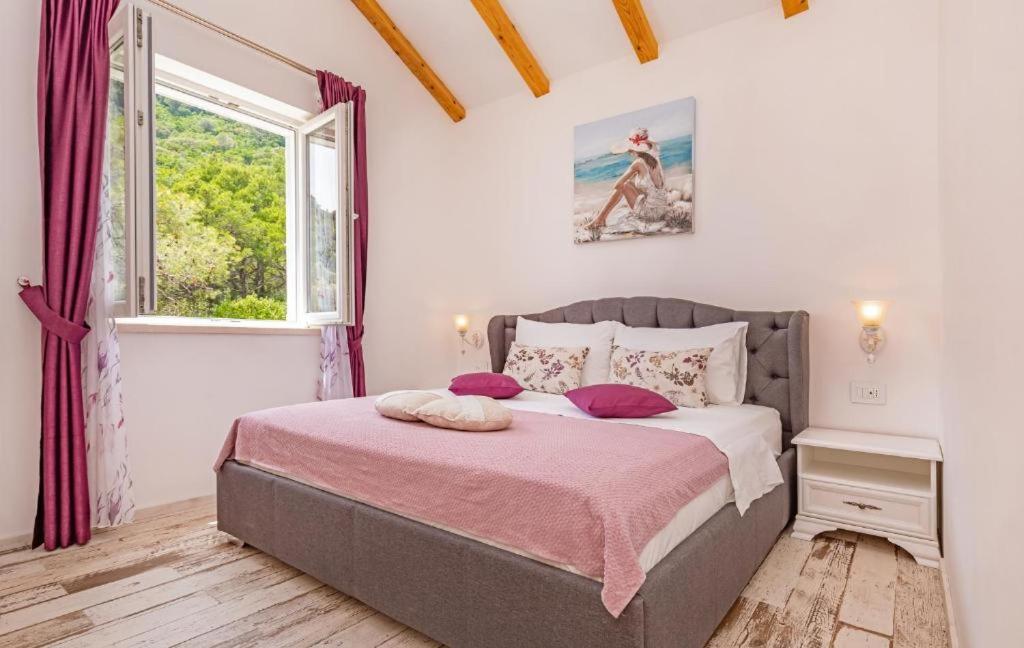 een slaapkamer met een bed met een roze deken en een raam bij Apartments More Luxury in Sobra