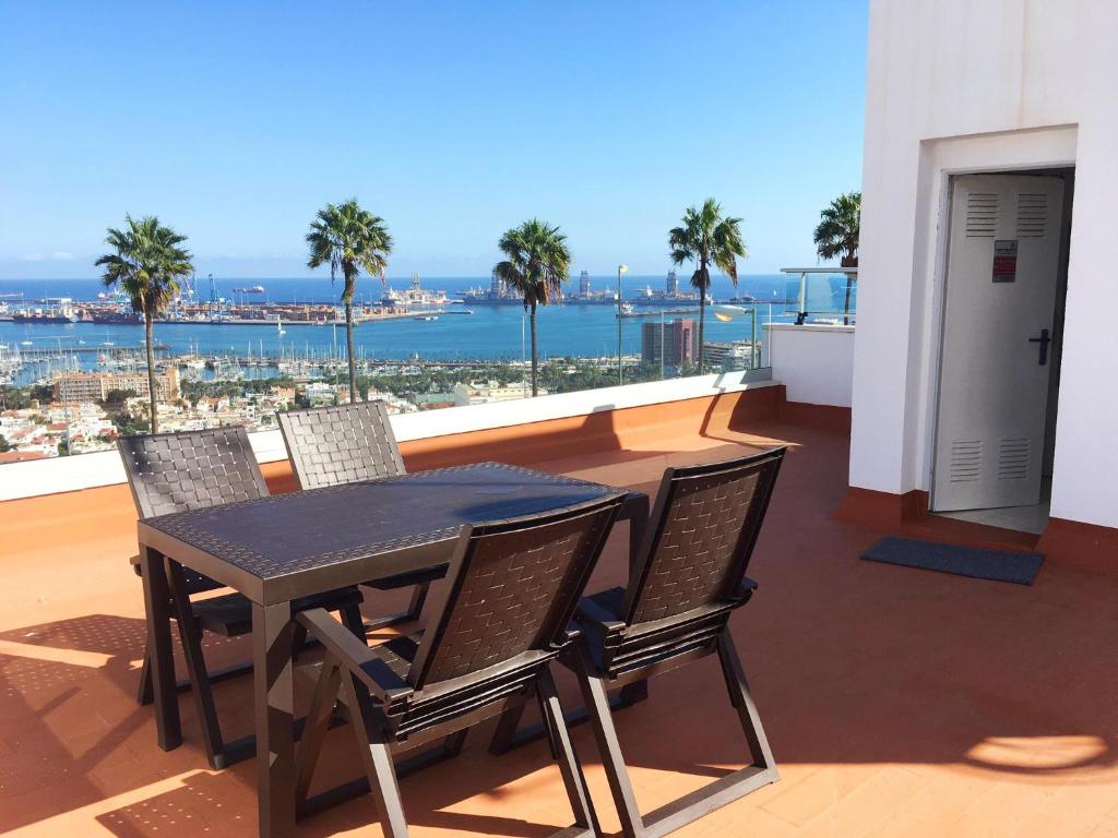 a table and chairs on a balcony with a view of the ocean at La Cornisa Villa by WaveProperties in Las Palmas de Gran Canaria