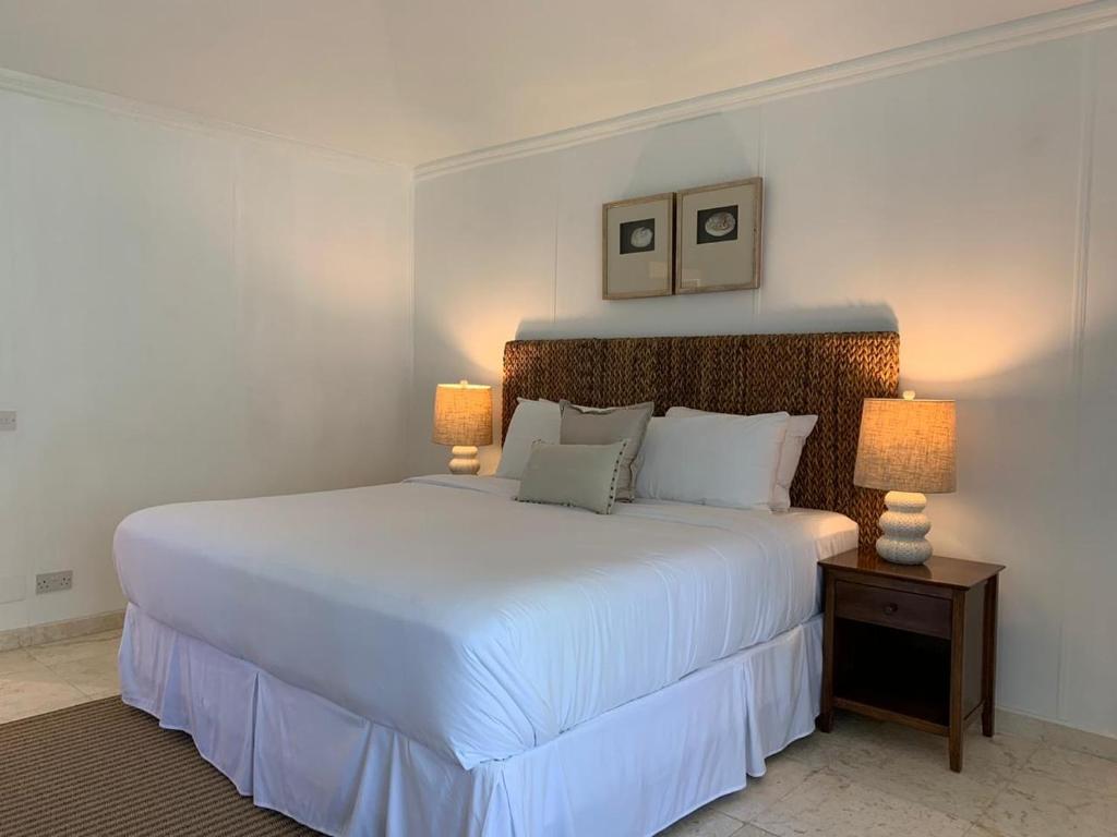 a bedroom with a large white bed with two lamps at Bequia Plantation Hotel in Bequia