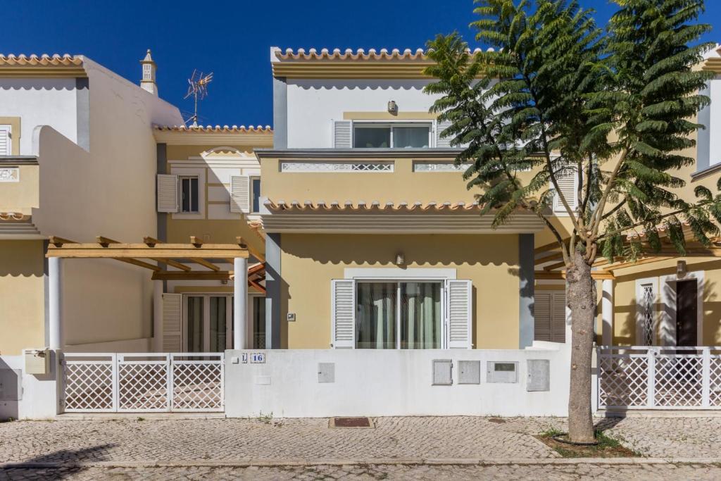 una casa con un árbol delante en Villa Amoreira by ALGARVEMANTA, en Manta Rota
