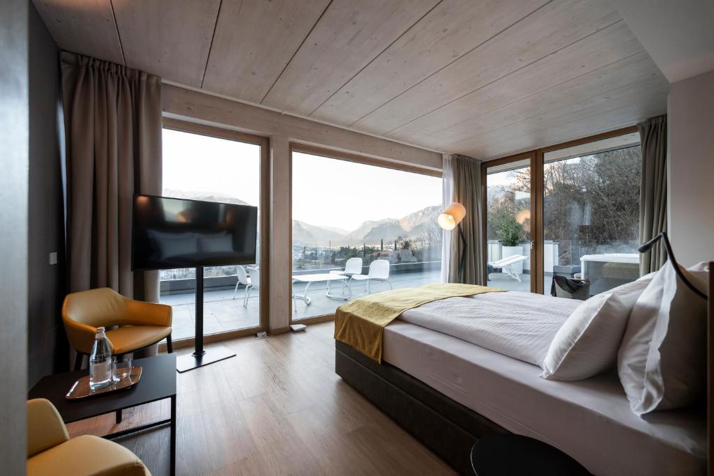 Schlafzimmer mit einem Bett, einem TV und einem Balkon in der Unterkunft Be Place Adult Friendly Hotel in Trient
