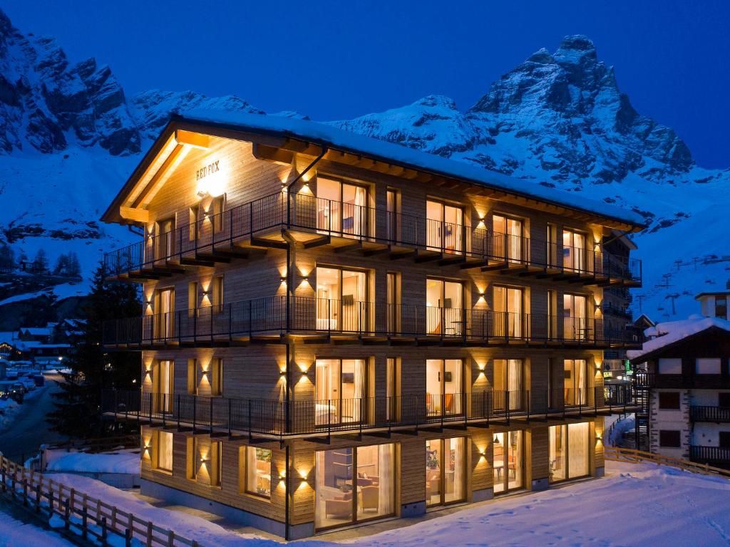 un bâtiment avec une montagne en arrière-plan dans l'établissement Red Fox Lodge, à Breuil-Cervinia