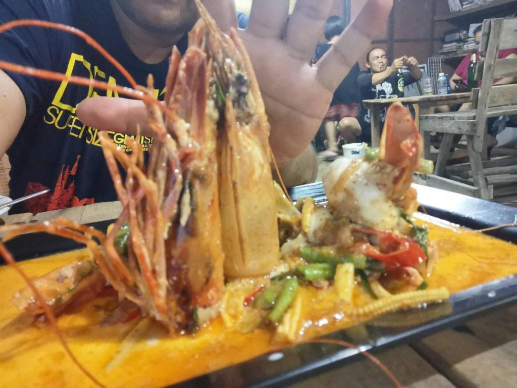 a person holding up a plate of food with shrimp at PP Red Tuna Hut in Phi Phi Don