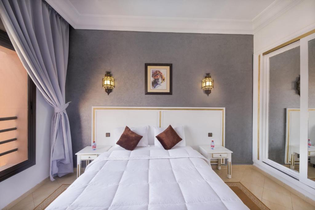 1 dormitorio con 1 cama blanca grande y 2 mesas en Mogador Menzah Appart Hôtel en Marrakech