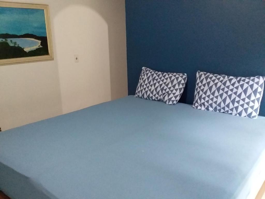 uma cama azul com duas almofadas em cima em Suites próximo ao rio Jaguareguava em Bertioga em Bertioga