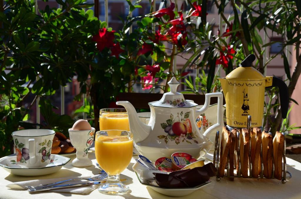 a table with a teapot and cups and orange juice at B&B SPLENDIDAE MUNDI in Rome