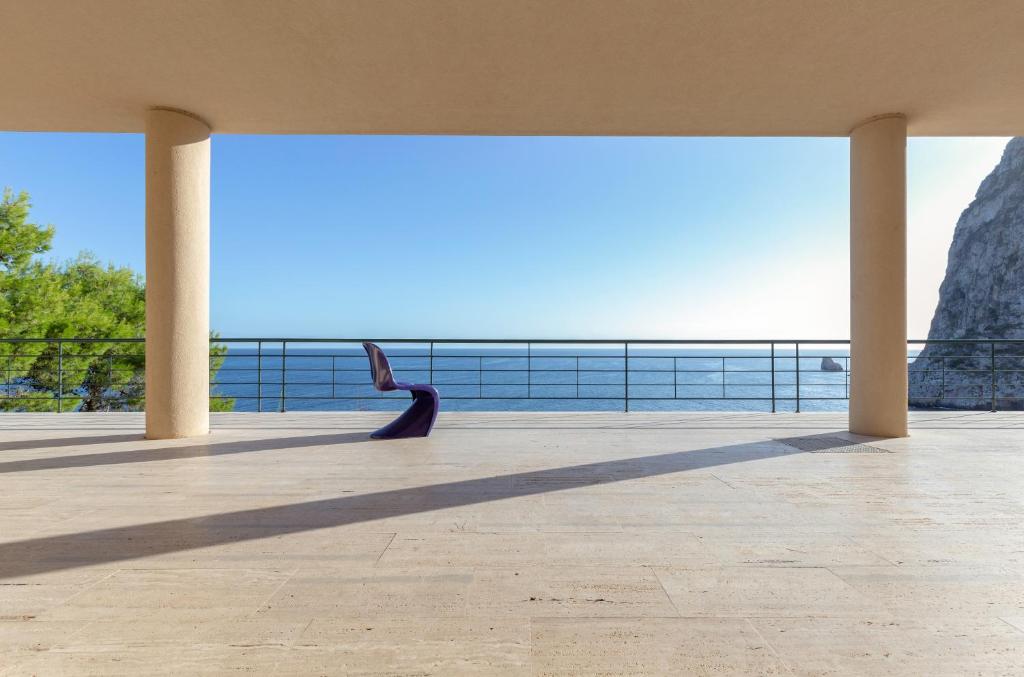 a person is sitting on a patio looking out at the ocean at Seaside Villa in Bagheria