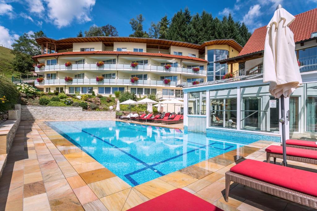 a hotel with a swimming pool in front of a building at Naturparkhotel Adler in Wolfach