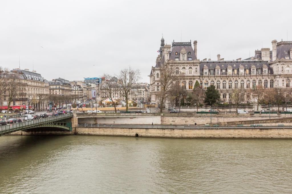 een brug over een rivier in een stad met gebouwen bij Veeve - Quai aux Fleurs Apartment in Parijs