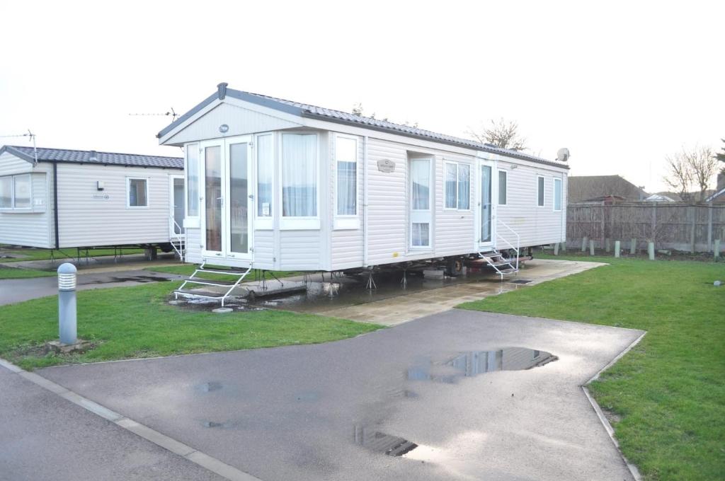 a white mobile home sitting in a parking lot at Caravan by Camber Sands in Camber