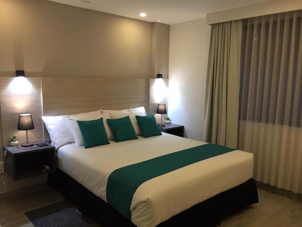 Habitación de hotel con cama grande con almohadas verdes en Suite Ejecutiva Ardres Plaza, en Quito