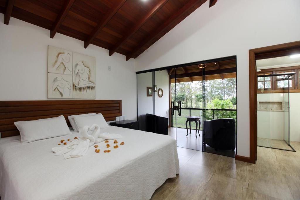 a bedroom with a large white bed with a glass door at Estancia Jacy in Alto Paraíso de Goiás