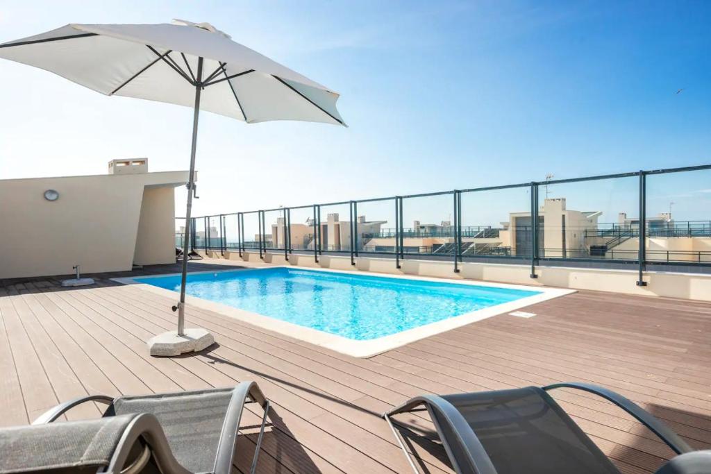 a pool on the roof of a building with an umbrella at ★ OCEANFRONT: Luxury Breathtaking Views and Pool ★ in Olhão