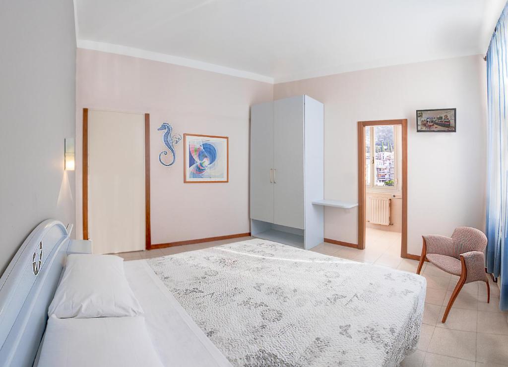 a white bedroom with a bed and a chair at Villa Pozzi in Sestri Levante