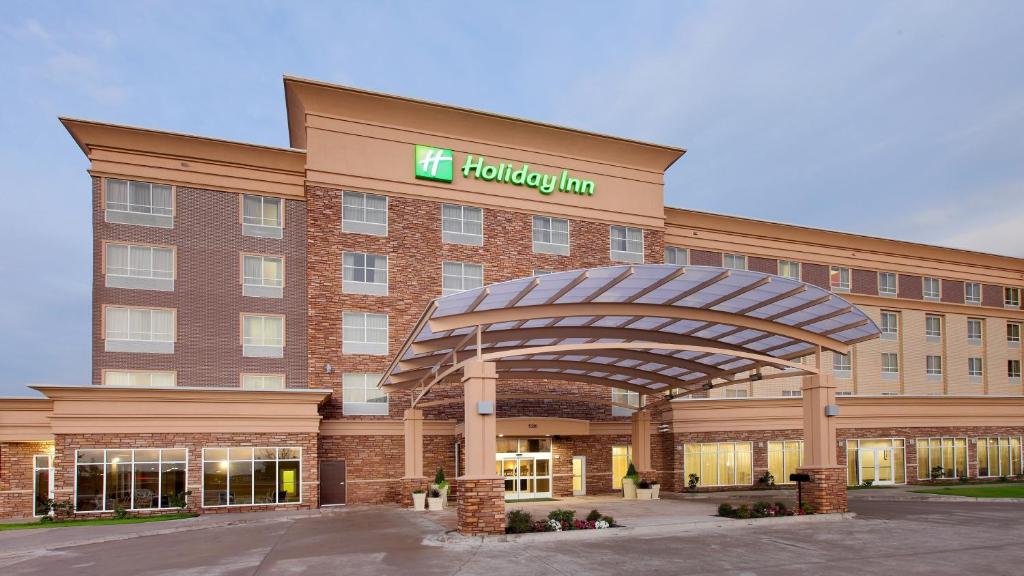 a hotel with a sign on the front of a building at Holiday Inn Garland, an IHG Hotel in Garland