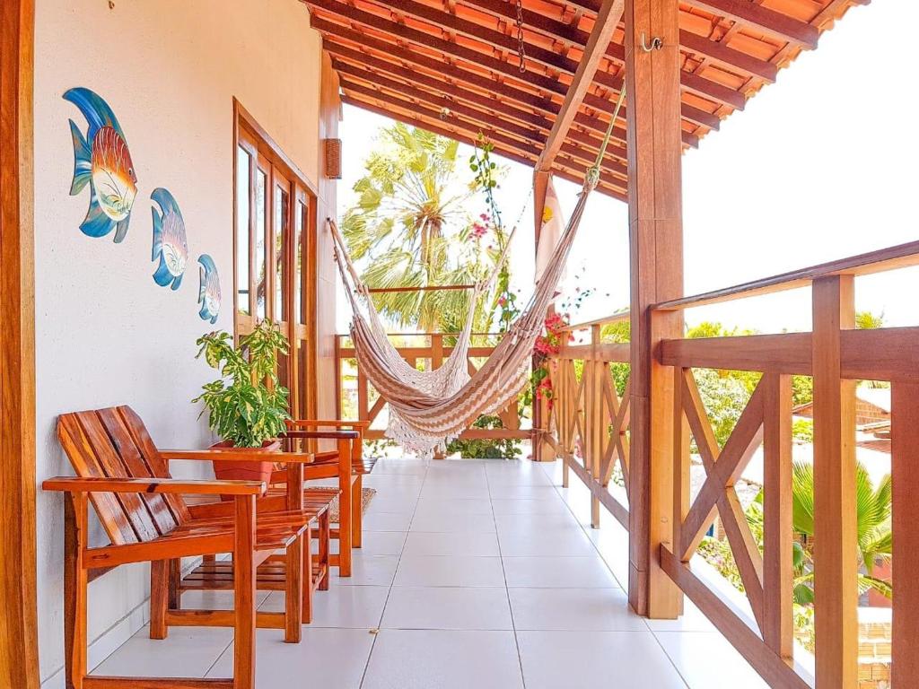 um alpendre com cadeiras e uma rede de descanso numa casa em Flats Villa Gelú em Barra Grande