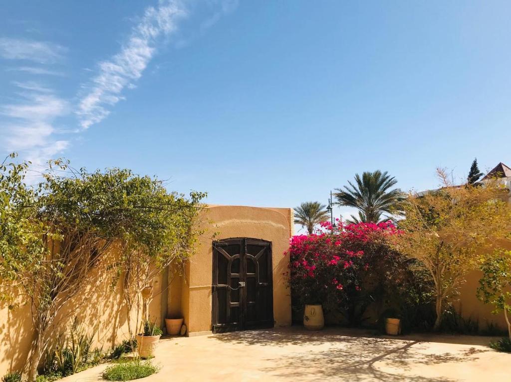 eine Tür zu einem Haus mit rosa Blumen in der Unterkunft Maison D'Hôtes villa Fatima in Tozeur