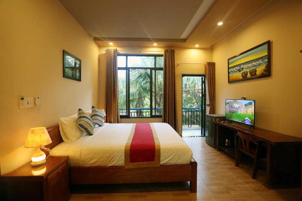 um quarto com uma cama, uma televisão e uma janela em Tan Doan An Bang center beach villas em An Bàn (2)