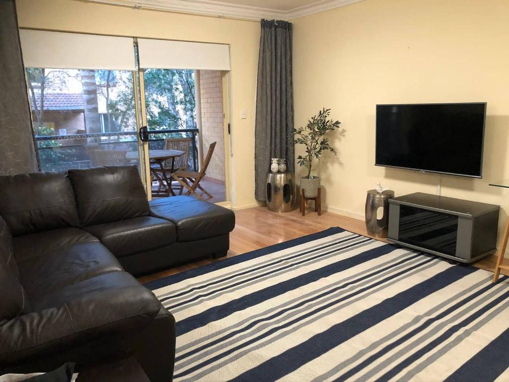 a living room with a couch and a flat screen tv at Escape to Strathfield for 8 guests in Sydney