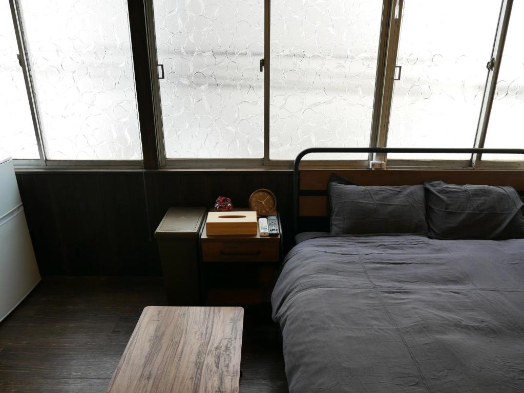1 dormitorio con cama, mesa y ventanas en GUEST HOUSE KISHINOSATO, en Osaka
